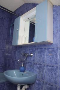 a blue tiled bathroom with a sink and a mirror at Ema Apartman in Livno