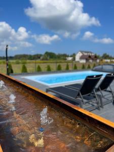 a swimming pool with two chairs next to a swimming pool at Loox Ostrovo- Boutique House-noclegi nad morzem in Ostrowo