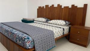 a bed with a wooden headboard and pillows on it at Appartement Luxueux vu sur mer à 50 mètres de la plage in Sali Tapé