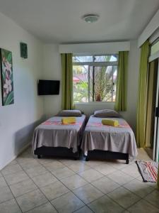 two beds in a room with a window at Pension ANAPA LODGE - MOOREA in Vaianae