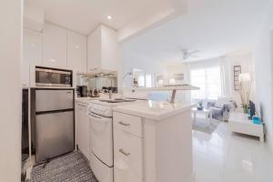 eine Küche mit weißen Geräten und ein Wohnzimmer in der Unterkunft OCEAN & SAND ONLY 1 MINUTE WALK! in Miami Beach