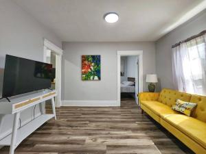 ein Wohnzimmer mit einem gelben Sofa und einem Flachbild-TV in der Unterkunft Tastefully furnished repose home in Springfield