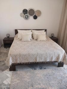 una camera da letto con un grande letto con cuscini e cappelli appesi al muro di Appartement en bord de mer a Monastir