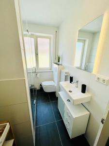 uma casa de banho com um WC, um lavatório e um espelho. em 3Room-Central-Modern- The Seashell by SA-Grandeur em Friedrichshafen