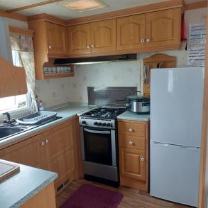 a kitchen with a stove and a white refrigerator at warden springs caravan park MS16 Thornhill road, Eastchurch,ME124HF in Sheerness