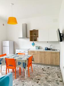 una cocina con mesa y algunas sillas naranjas en Conero-30 mt dal Mare, Balcone V i s t a Mare e Spiaggia di sabbia en Porto Potenza Picena