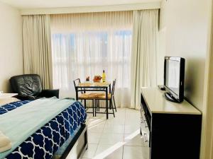 a bedroom with a bed and a table with a television at APARTMENT RIGHT ON THE BEACH! in Miami Beach