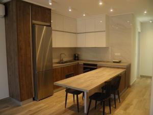 a kitchen with a wooden table and a stainless steel refrigerator at Anemolia Elegant Apartment in Karistos