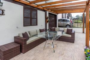 un patio con una mesa de cristal y 2 sofás en Apartamento Completo de 3 quartos em Gramado 2, en Gramado