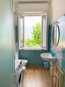 uma casa de banho com uma janela, um lavatório e um WC. em Conero-30 mt dal Mare, Balcone V i s t a Mare e Spiaggia di sabbia em Porto Potenza Picena