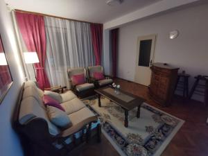uma sala de estar com um sofá, cadeiras e uma mesa em Apartman Monaco em Kraljevo