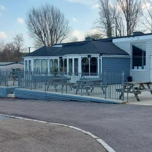 a white house with a fence and a picnic table at warden springs caravan park MS16 Thornhill road, Eastchurch,ME124HF in Sheerness