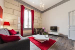 Una sala de estar con un sofá y un televisor. en Du Guesclin Comédie (connecté & climatisé), en Montpellier