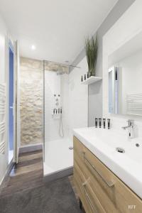 uma casa de banho branca com um chuveiro e um lavatório. em Du Guesclin Comédie (connecté & climatisé) em Montpellier