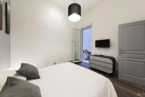 a white bedroom with a bed and a tv at Du Guesclin Comédie (connecté & climatisé) in Montpellier