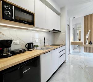a white kitchen with a sink and a microwave at B&K ROOMS in Heraklio