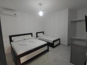 Habitación pequeña con 2 camas y paredes blancas. en Guesthouse Leo, en Ksamil