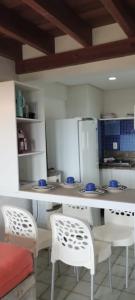a kitchen with white chairs and a white counter top at Ancorar Flat in Porto De Galinhas