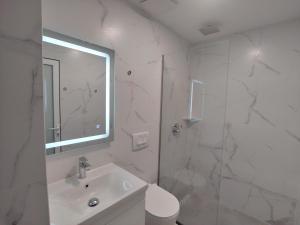 y baño blanco con lavabo y ducha. en Guesthouse Leo, en Ksamil