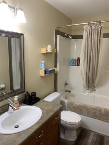 a bathroom with a sink and a toilet and a shower at Dragonfly Inn Walkout Suites in Sherwood Park +50 photos