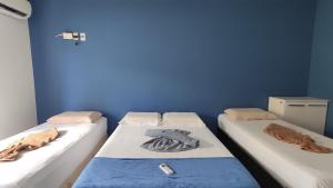 drie bedden in een kamer met een blauwe muur bij Casa Janga Mar in Barra de São Miguel