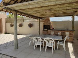 a patio with a table and chairs and a fireplace at Casa Janga Mar in Barra de São Miguel