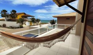 een hangmat op een balkon met uitzicht op de oceaan bij Casa Janga Mar in Barra de São Miguel