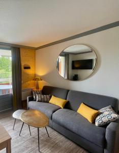 ein Wohnzimmer mit einem Sofa und einem Spiegel in der Unterkunft Pierre et Vacances Les Bergers - Piscine Sauna in L'Alpe-d'Huez