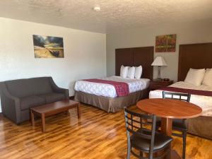 a hotel room with two beds and a table and a couch at Red Carpet Inn Medford in Medford