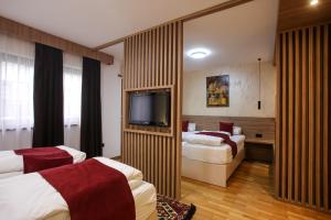 a hotel room with two beds and a flat screen tv at Hotel Emen in Mostar