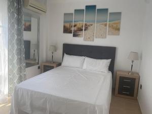 a bedroom with a white bed with two tables and two lamps at Beach Apartment La Cala de Mijas in La Cala de Mijas