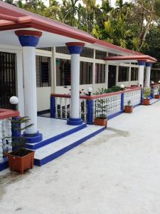 Sunapur Mini Resort Sylhet في سيلهيت: مبنى فيه اعمدة و نباتات زرقاء و بيضاء