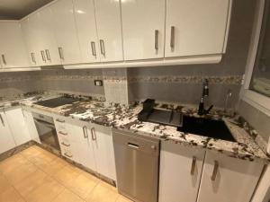 a kitchen with white cabinets and marble counter tops at Beach Apartment La Cala de Mijas in La Cala de Mijas +12 photos