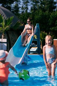 a woman and two children on a slide in a pool at Hotel Kotarz Spa&Wellness in Brenna