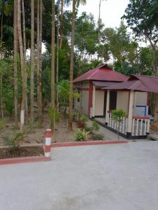 ein kleines Haus mit einer roten und weißen Stange davor in der Unterkunft Sunapur Mini Resort Sylhet in Sylhet