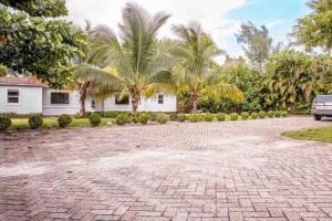 a brick driveway in front of a house with palm trees at HOT TUB HOUSE ON GOLF COURSE! 10 MINs TO THE BEACH in Miami