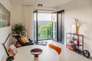 ein Wohnzimmer mit Tisch und großem Fenster in der Unterkunft BNBNRD Stylish Boutique Apartment 45m2 w Panoramic Views - private entrance in Amsterdam