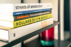 een stapel boeken op een plank bij BNBNRD 2-Room Boutique Apartment Amsterdam Cultural District in Amsterdam
