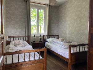 2 Einzelbetten in einem Schlafzimmer mit Fenster in der Unterkunft Le Moulin du Saon in Saon