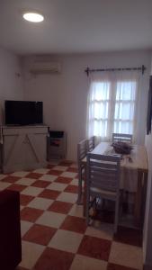 ein Wohnzimmer mit einem Tisch, Stühlen und einem TV in der Unterkunft Casa Isabella in Villa Dolores