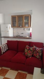 a red couch in a living room with a kitchen at Casa Isabella in Villa Dolores