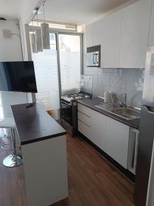 a kitchen with white cabinets and a black counter top at Departamento Ovalle 212 in Ovalle +2 photos