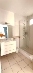 a white bathroom with a sink and a shower at Gite MAYO & HYLODE'S SONG in Bouillante