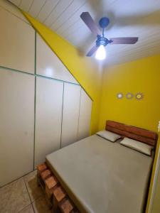 Habitación con cama y ventilador de techo. en Cantinho Feliz de Muriqui / Casa amarela en Mangaratiba