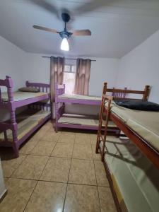 Zimmer mit mehreren Etagenbetten und einem Deckenventilator. in der Unterkunft Cantinho Feliz de Muriqui / Casa amarela in Mangaratiba