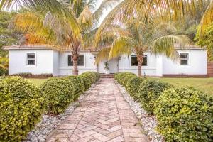a house with palm trees and a brick walkway at HOUSE WITH POOL, 10 MINS DRIVE TO THE BEACH! in Miami Shores