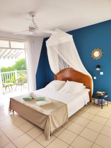 1 dormitorio con cama y pared azul en Gite MAYO & HYLODE'S SONG, en Bouillante