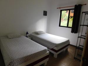 two twin beds in a room with a window at Villasjungle 2 in Sámara