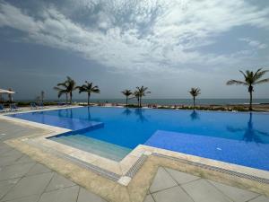 een groot zwembad met palmbomen en de oceaan bij Casa de Amor Sifa in As Sīfah