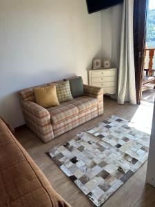 a living room with a couch and a rug at Raio de Sol na Montanha in Campos do Jordão